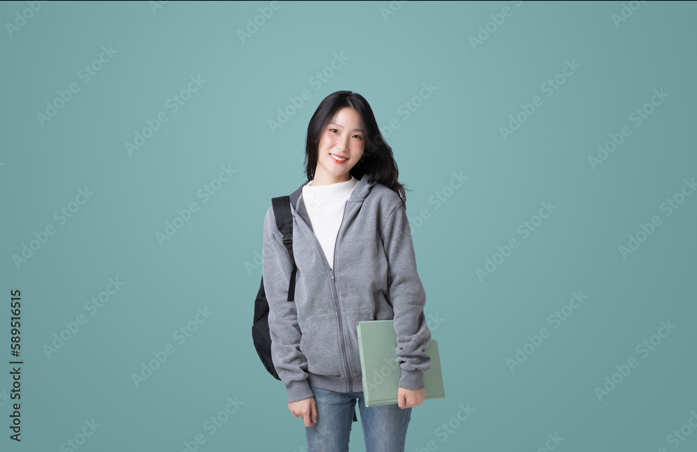 Young Asian girl college student with tablet and backpack isolated over teal background