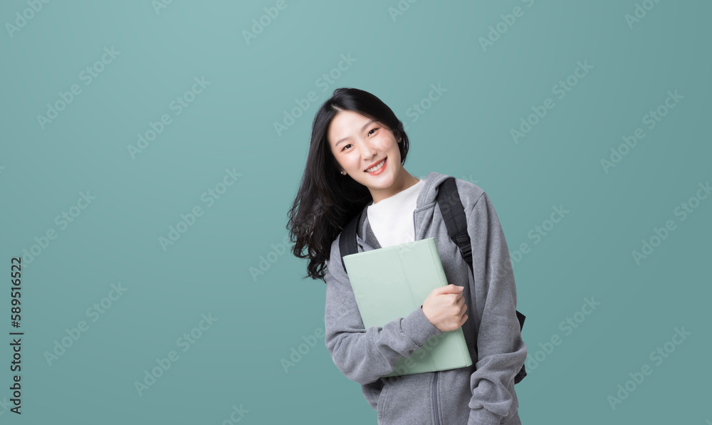 Young Asian girl college student with tablet and backpack isolated over teal background