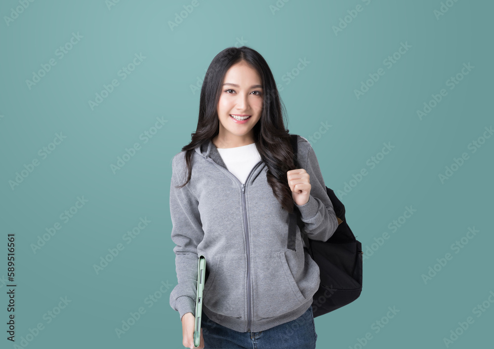 Young Asian girl college student with tablet and backpack isolated over teal background