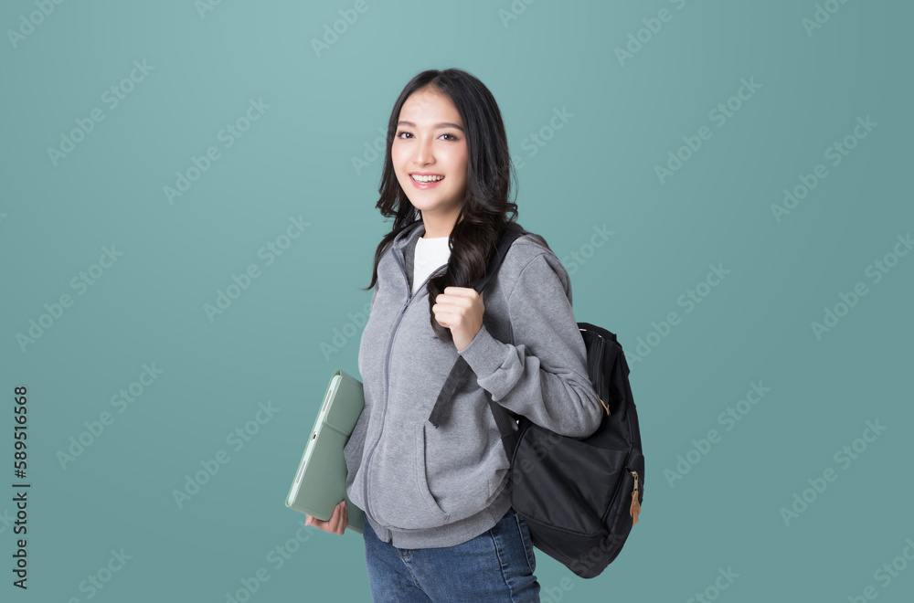 Young Asian girl college student with tablet and backpack isolated over teal background