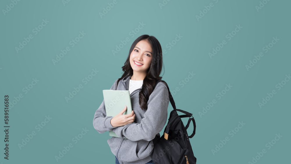 Young Asian girl college student with tablet and backpack isolated over teal background