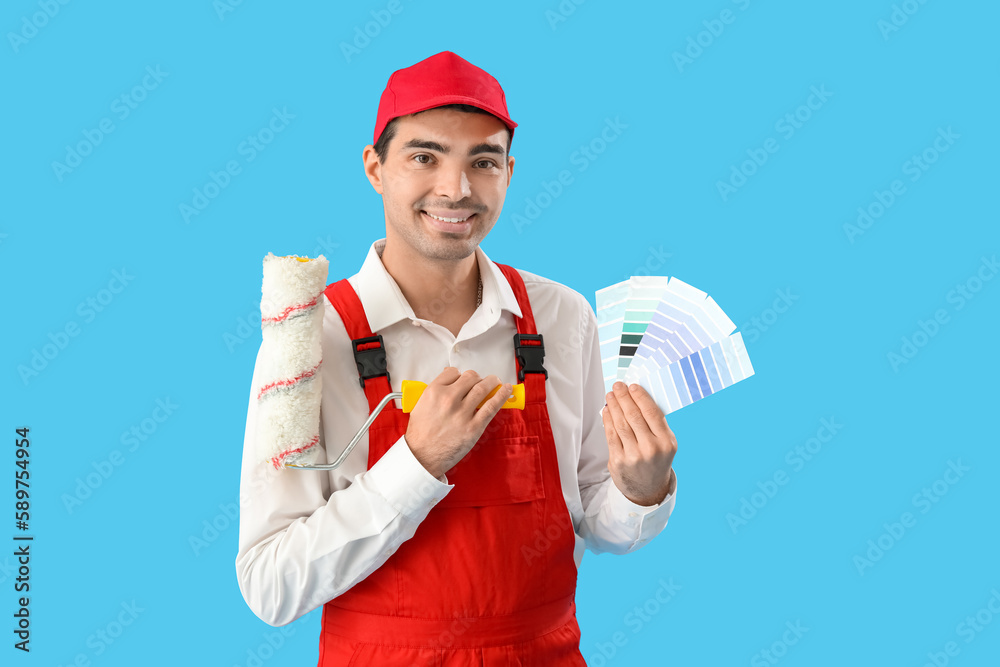 Male painter with color palettes and roller on blue background