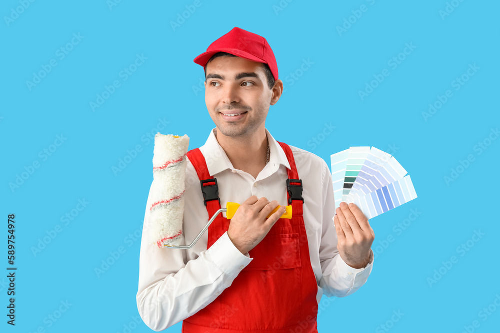 Male painter with color palettes and roller on blue background