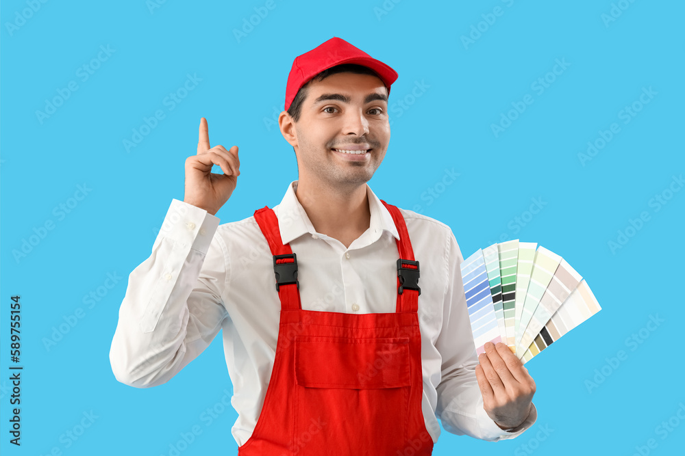 Male painter with color palettes pointing at something on blue background