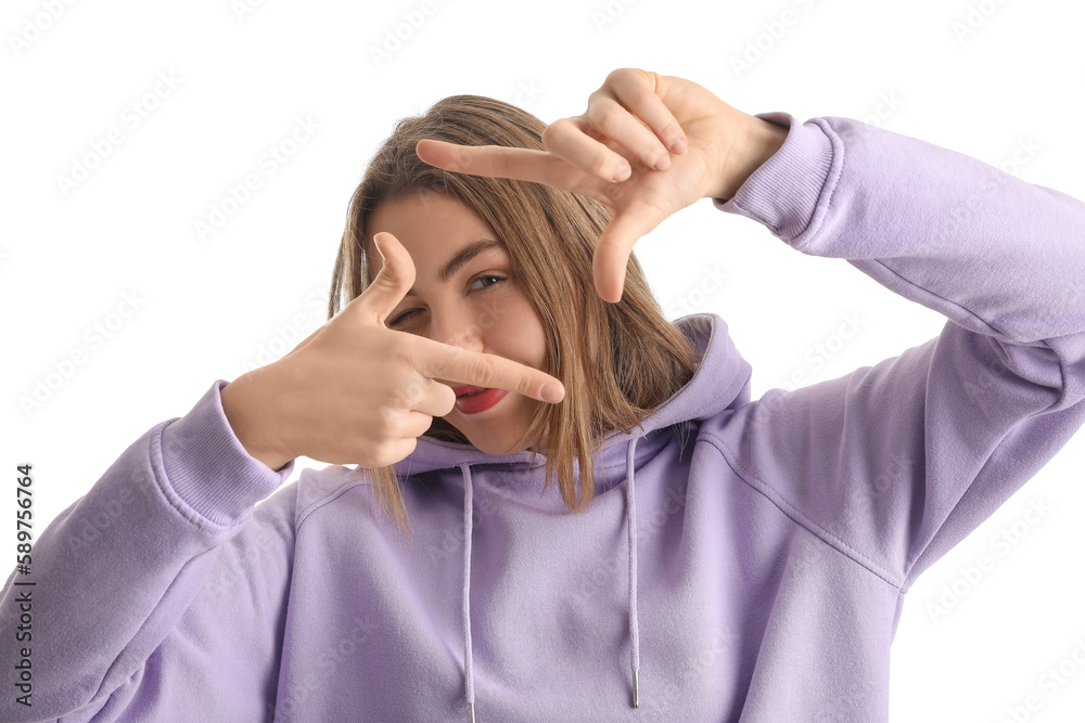 Young woman in lilac hoodie making frame with her hands on white background