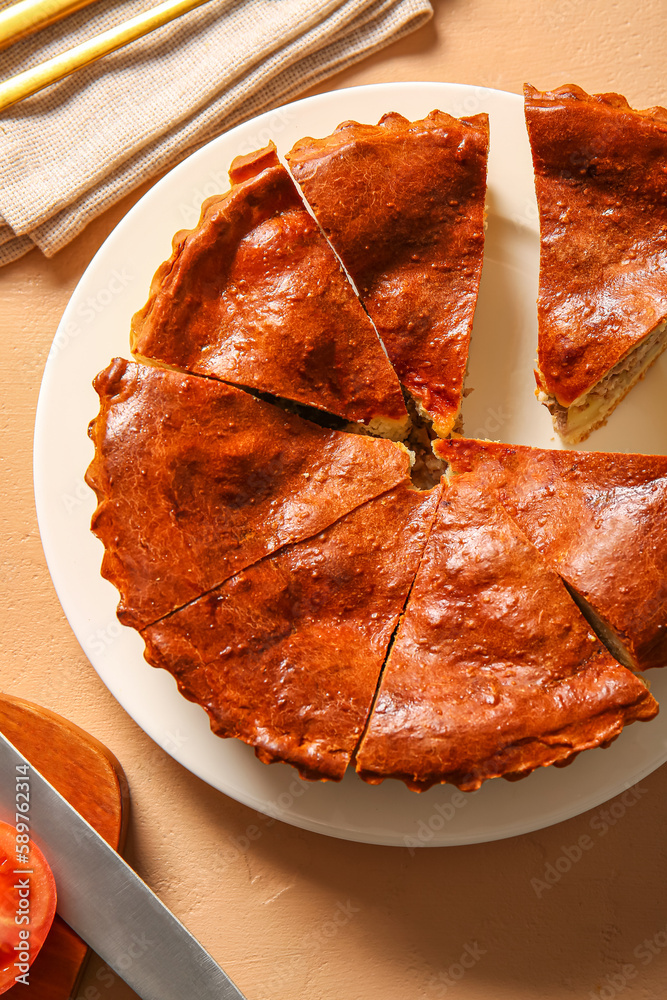 Plate with pieces of delicious meat pie on beige table, closeup