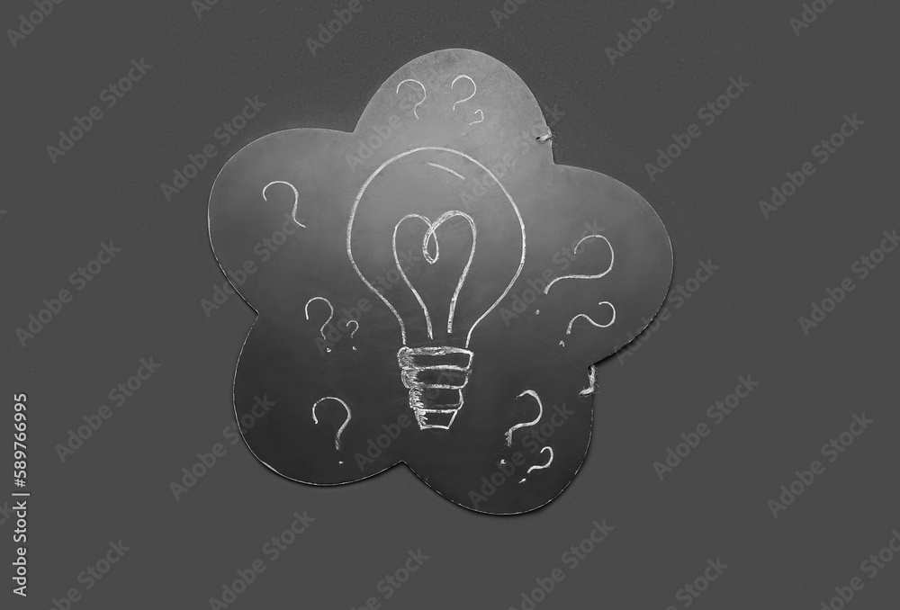 Chalkboard with drawn light bulb and question marks on black background. Insight concept