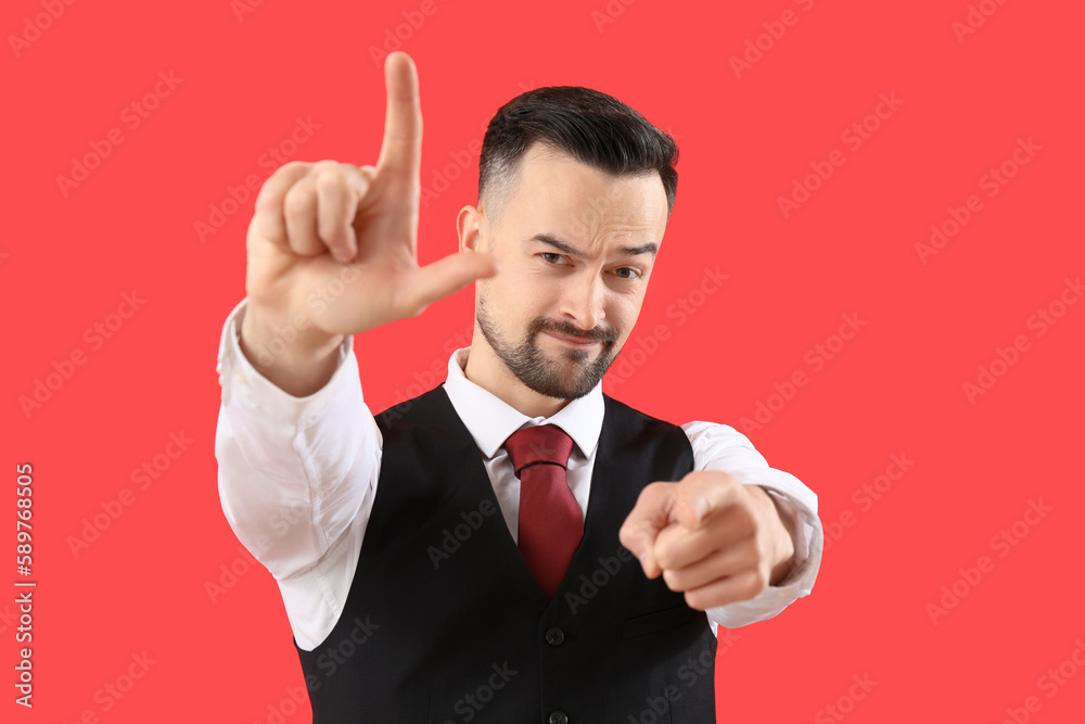 Handsome man showing loser gesture on red background