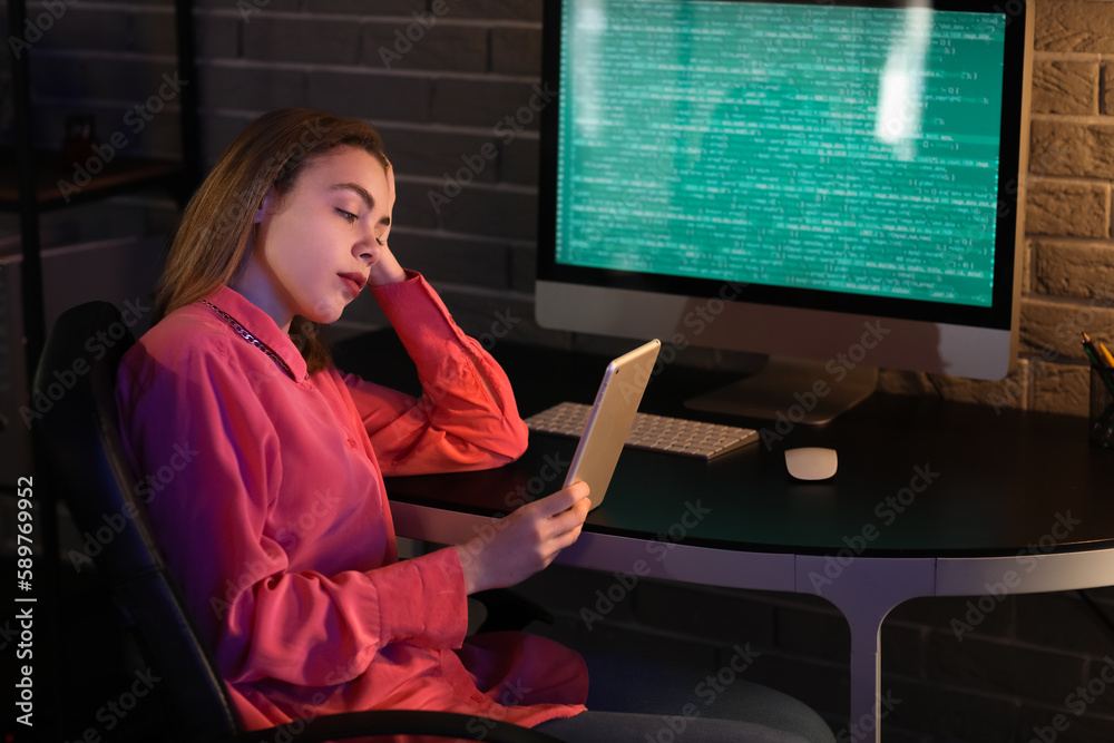 Female programmer working with tablet computer in office at night