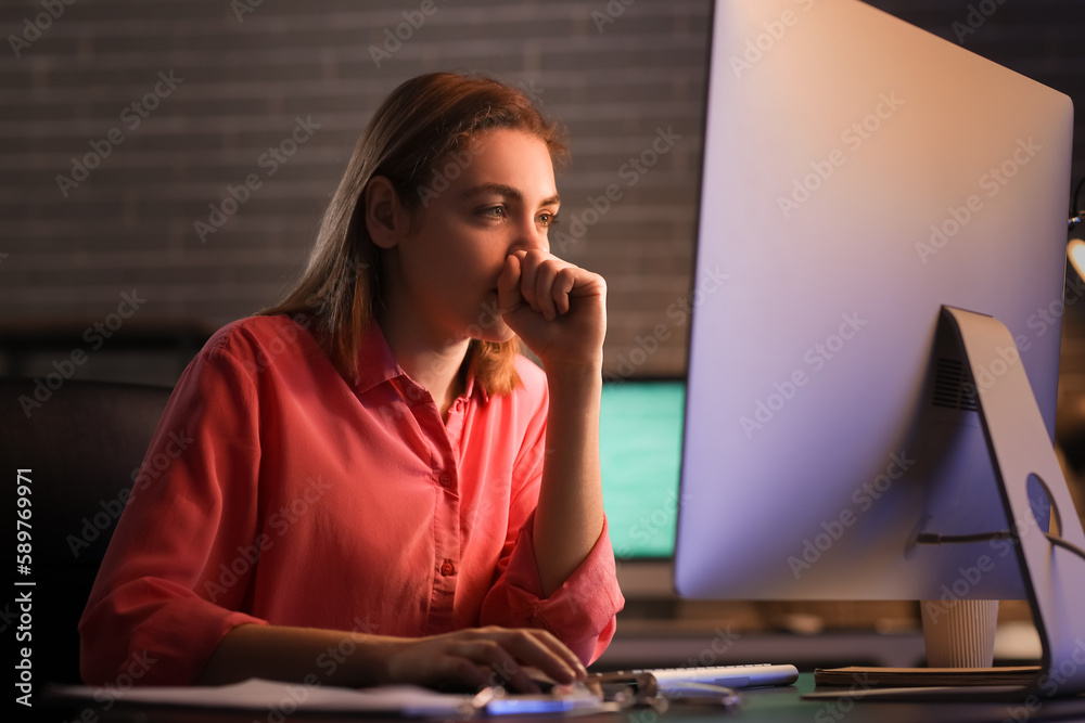 Female programmer working with computer in office at night