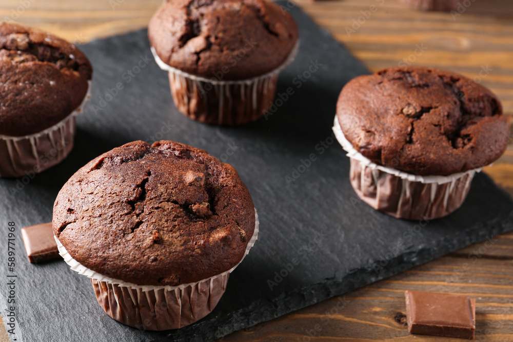 Board with tasty chocolate cupcakes on wooden background