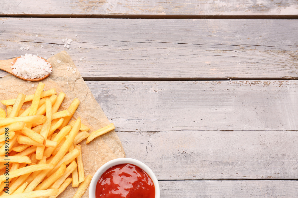 Tasty french fries, salt and ketchup on wooden background