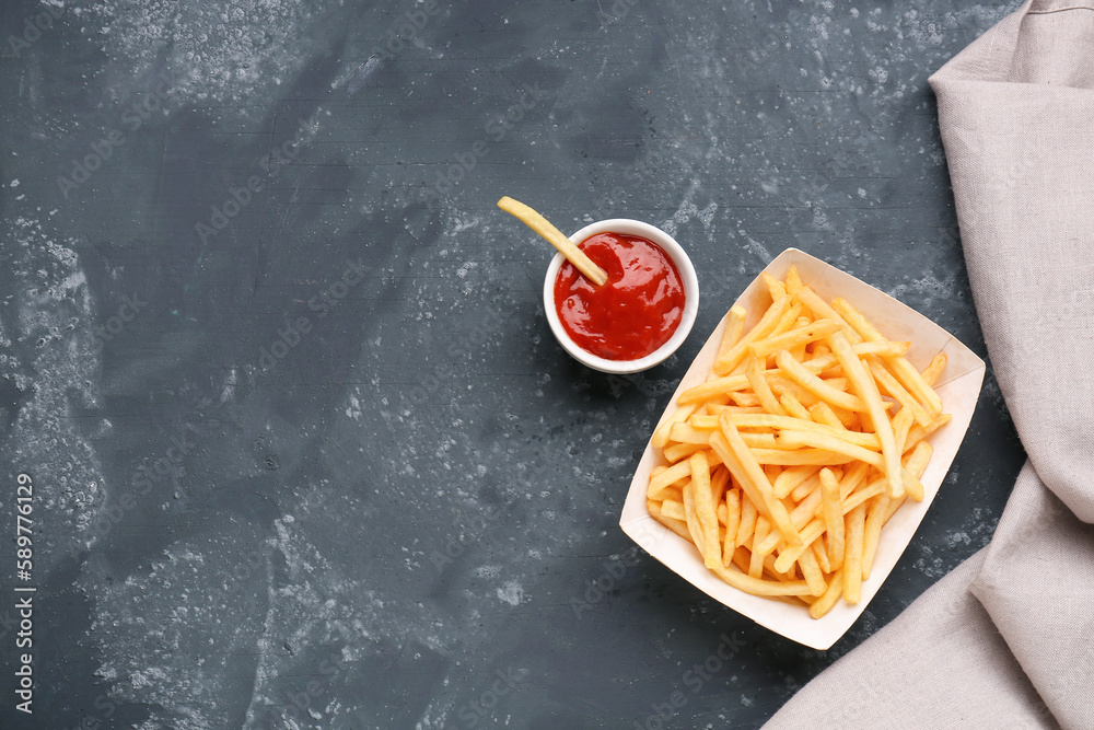 Paper box with tasty french fries and ketchup on dark grey background