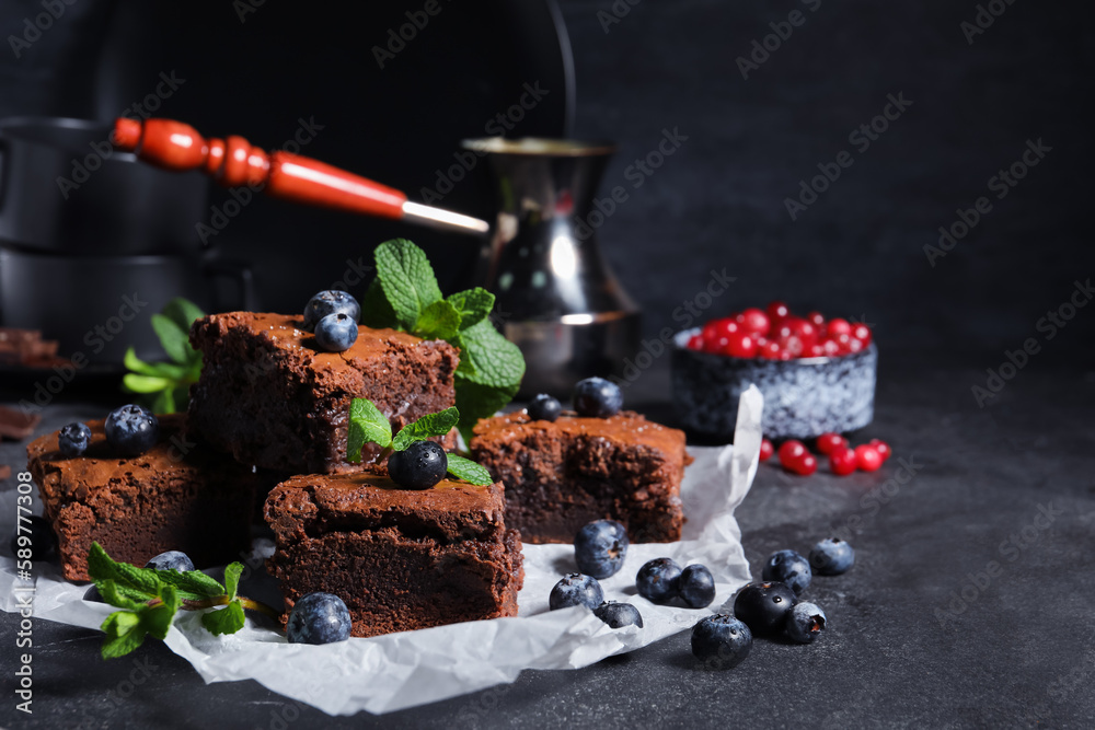 Pieces of tasty chocolate brownie on black background