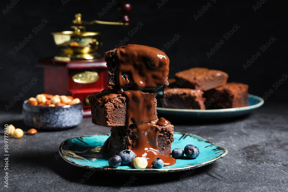 Plate with pieces of tasty chocolate brownie on black background