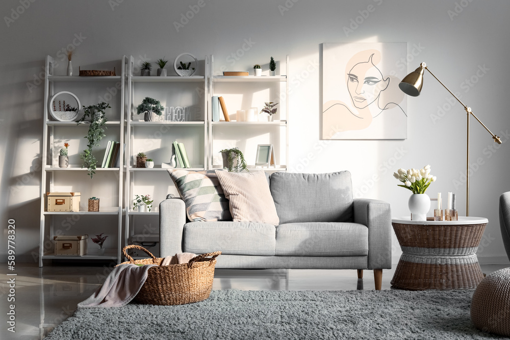 Interior of light living room with sofa, shelving units and artificial plants