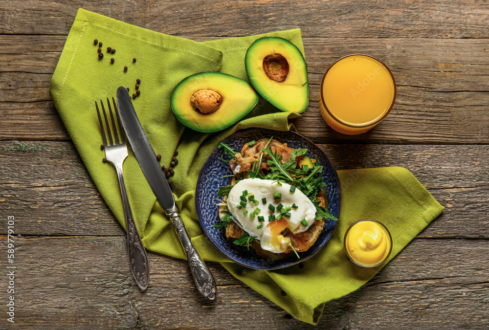 Plate with tasty egg Benedict and glass of juice on wooden background