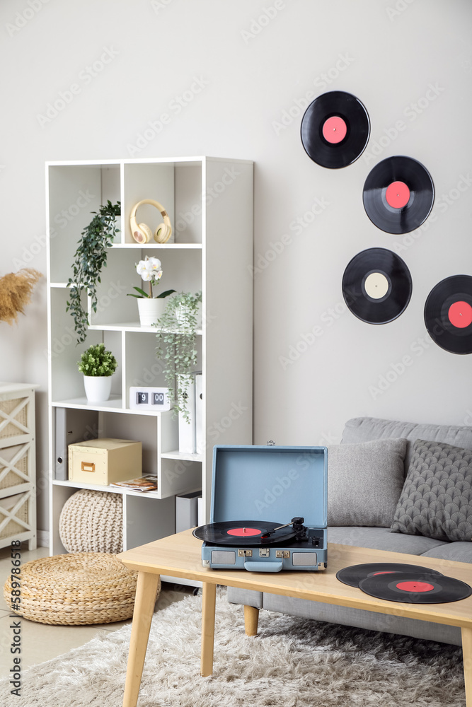 Record player with vinyl disks on table in interior of living room