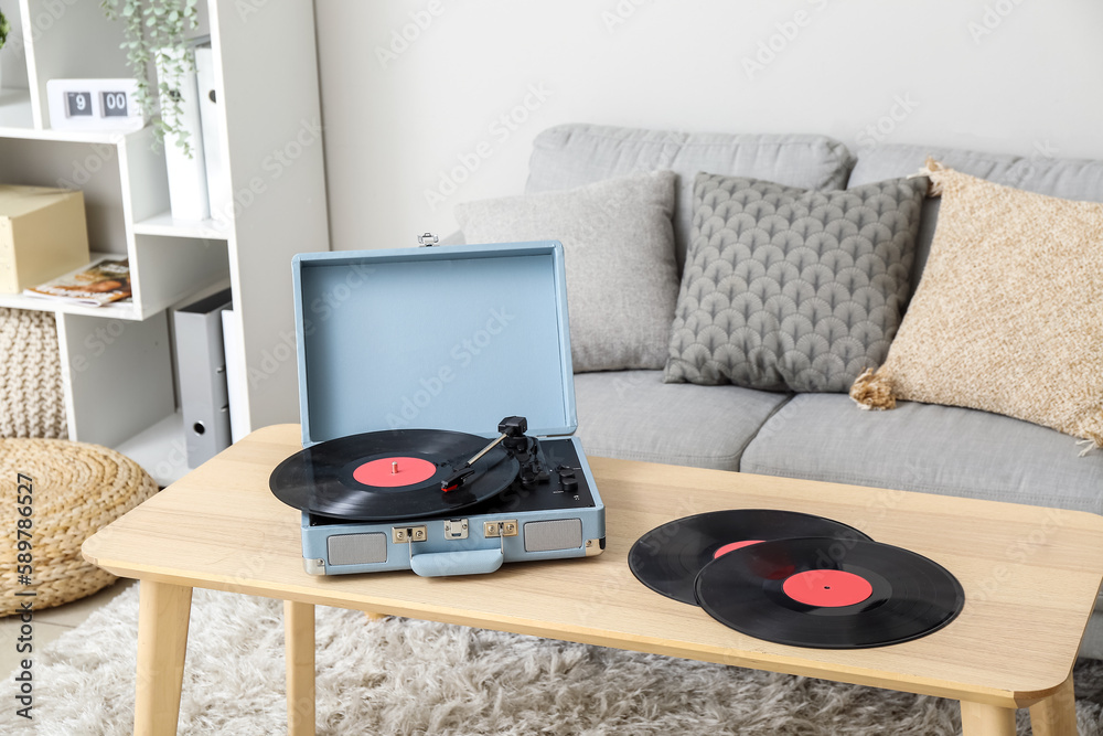 Record player with vinyl disks on table in living room