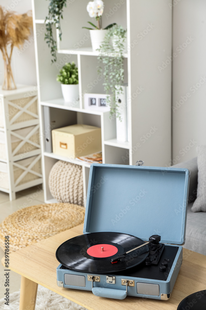 Record player with vinyl disk on table in living room