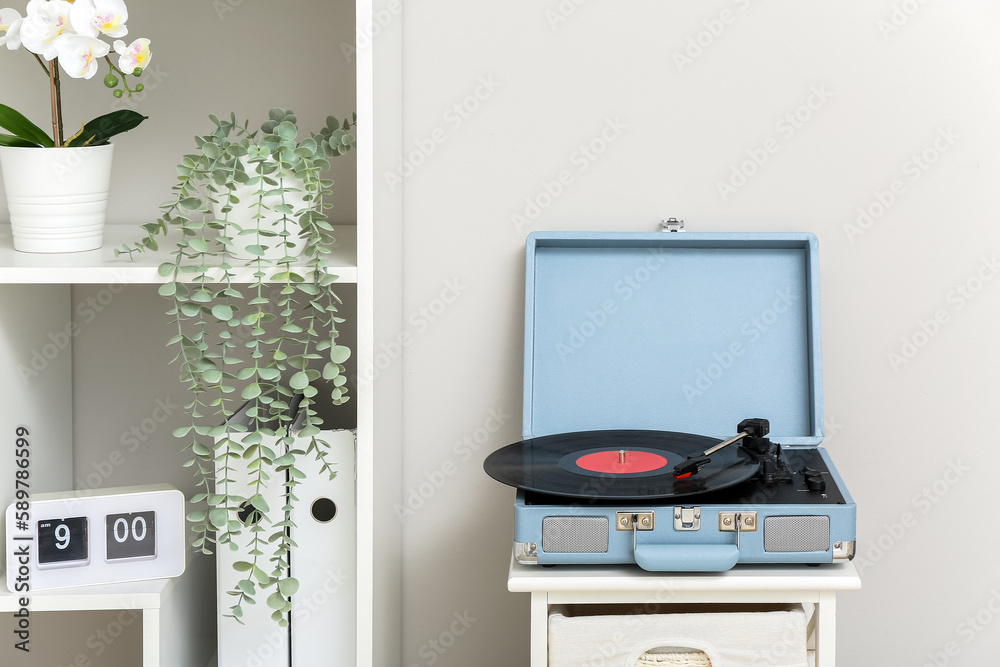 Record player with vinyl disk on shelf in living room