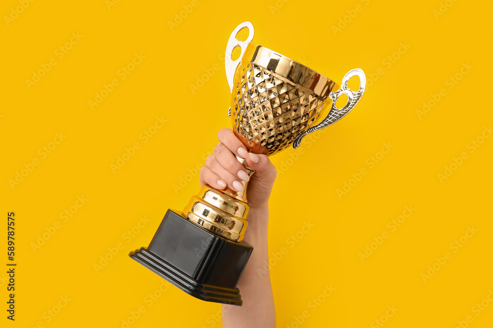 Woman with gold cup on yellow background