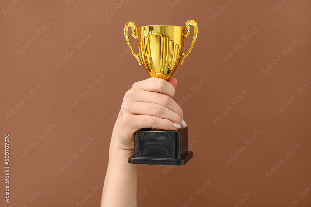 Woman with gold cup on brown background