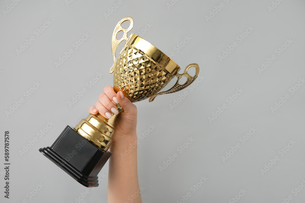 Woman with gold cup on grey background