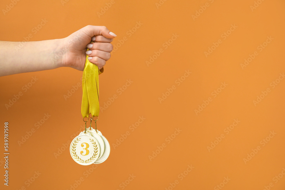 Woman with prize medals on orange background