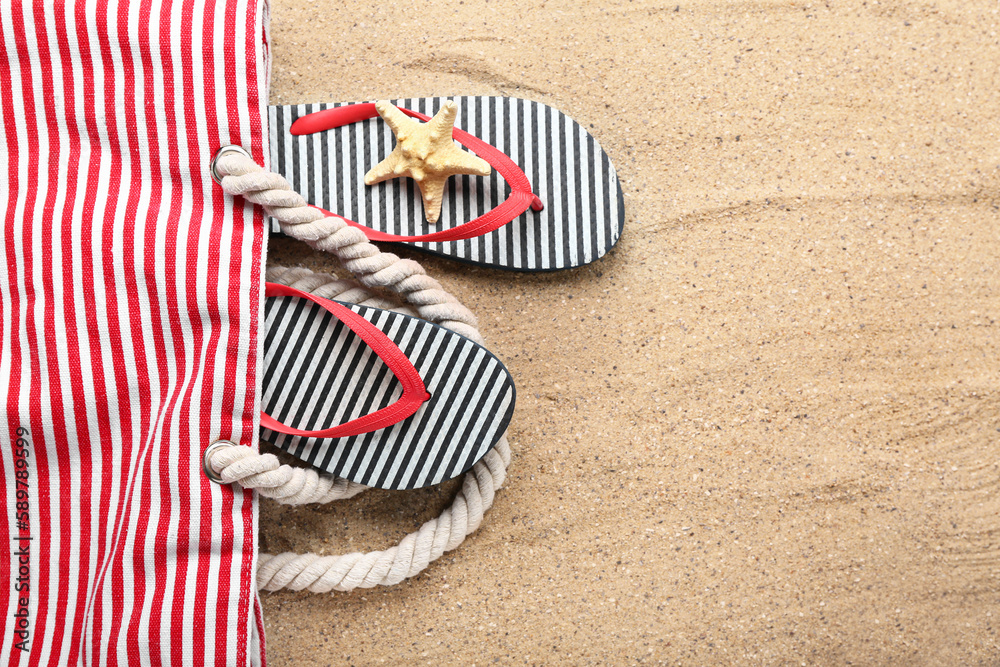 Bag with flip-flops and starfish on sand, closeup