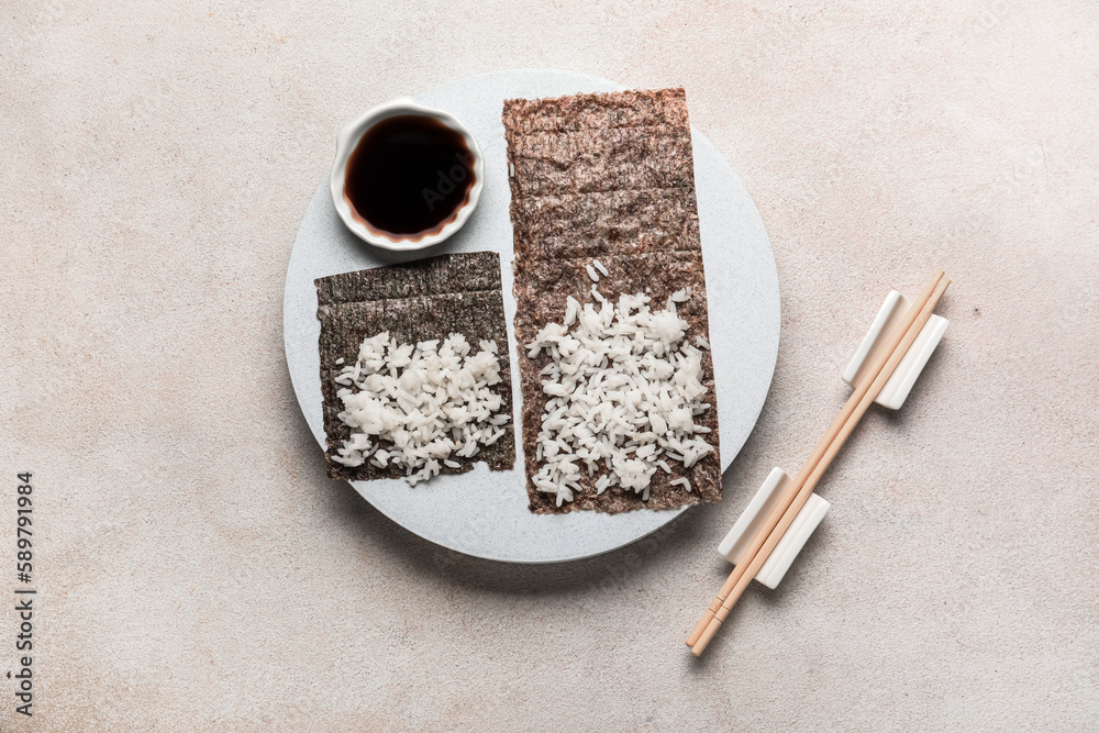 Wooden board of nori with rice and sauce on light background