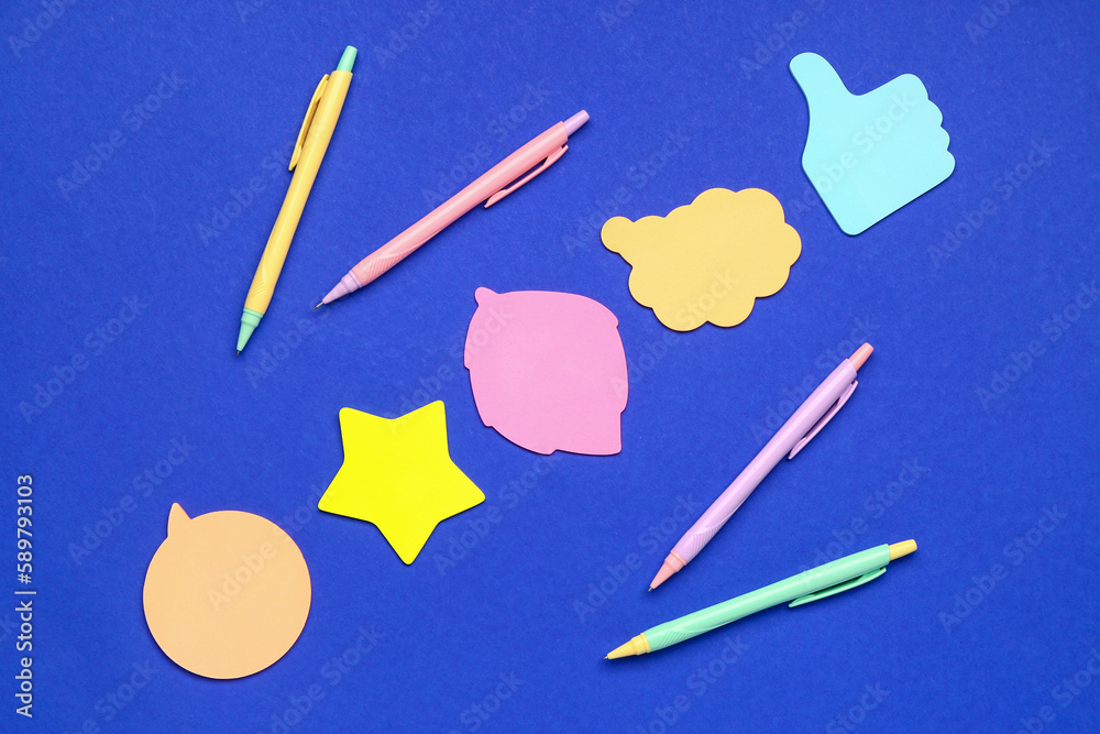 Colorful sticky notes and pens on blue background