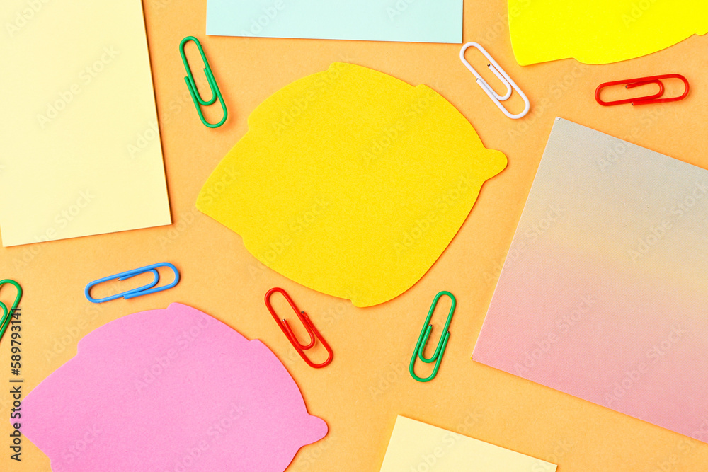 Colorful sticky notes and paperclips on yellow  background