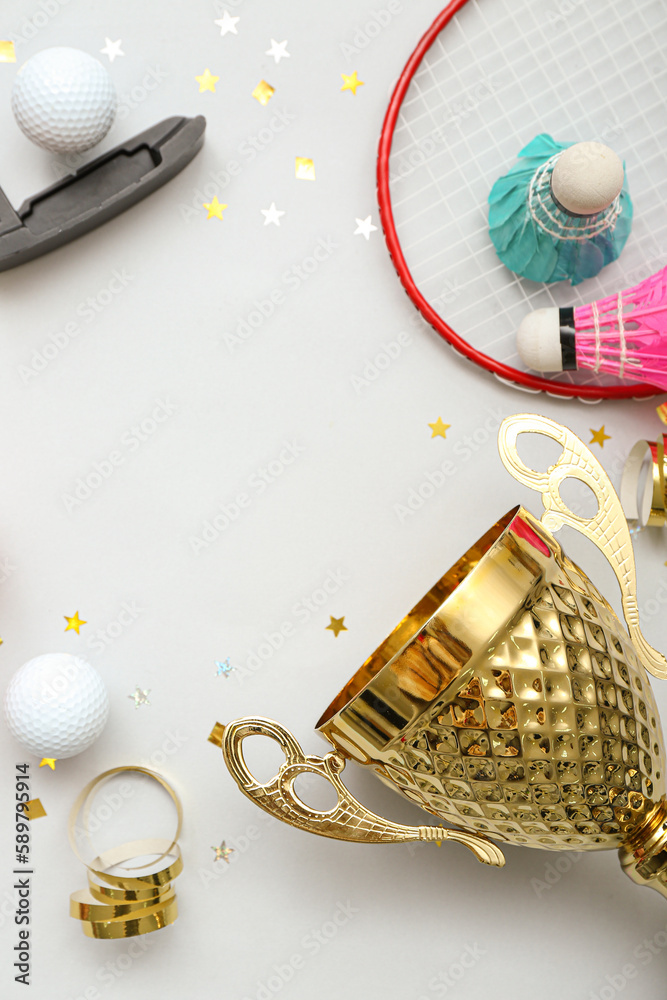 Frame made of gold cup with sports equipment and confetti on light background