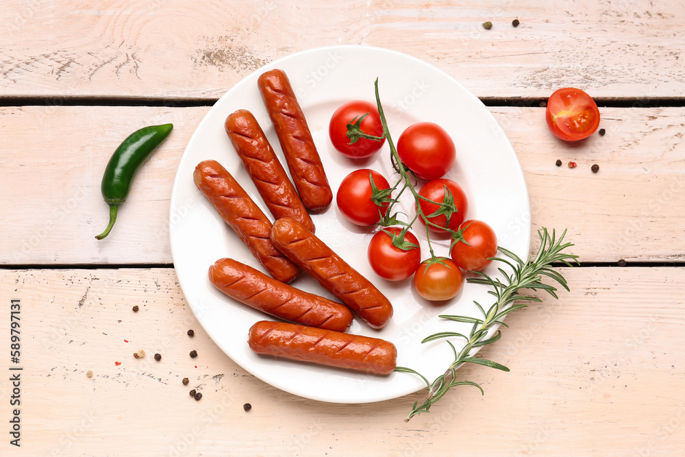 Plate with tasty grilled sausages and fresh tomatoes on light wooden background