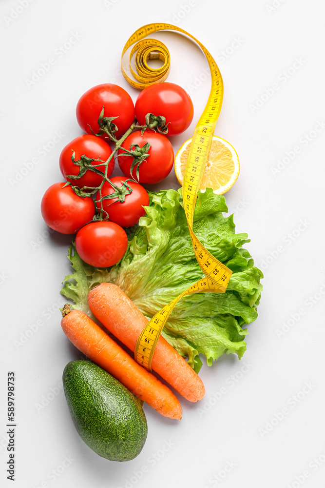 Vegetables, lemon and yellow measuring tape on grey background. Diet concept