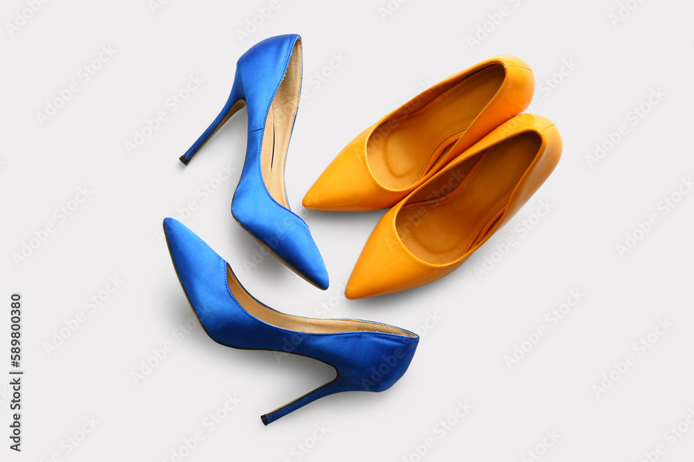 Stylish high heeled shoes on light background, top view