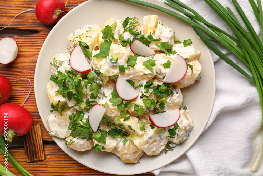 Plate of tasty Potato Salad with greens and radish on table