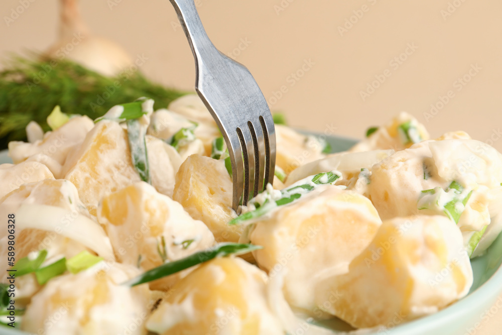 Plate of tasty Potato Salad with greens on yellow background, closeup