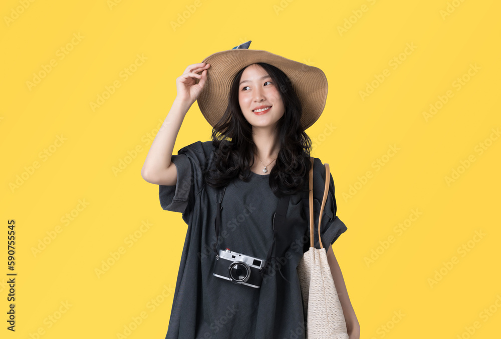 Young Asian woman Wearing a dress with a sun hat travel concept isolated on yellow background