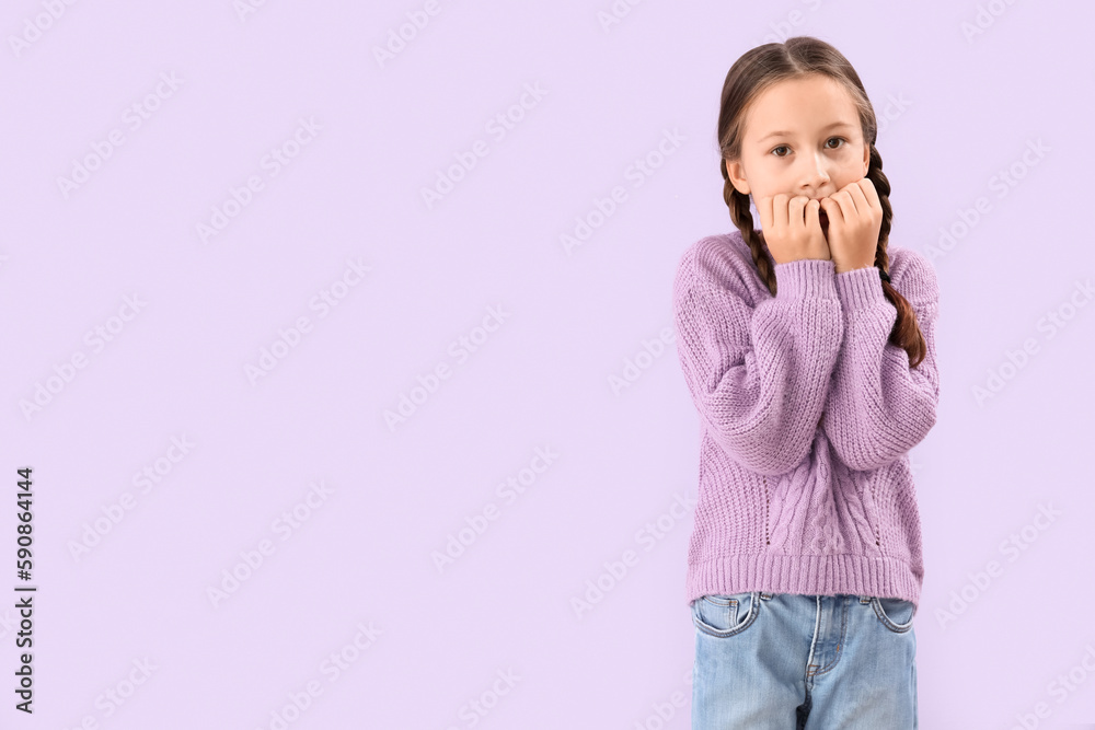 Little girl biting nails on lilac background