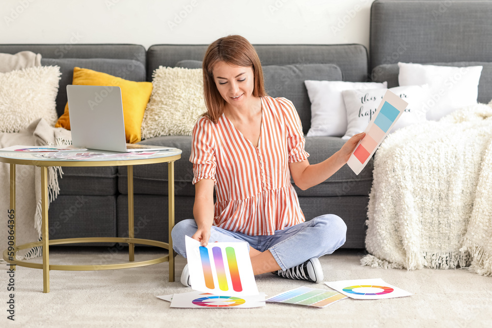 Young woman with paint color palettes sitting on floor at home