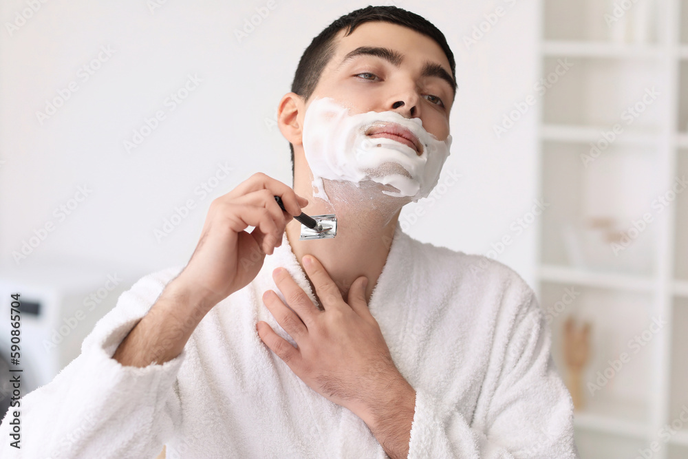 Young man shaving in bathroom