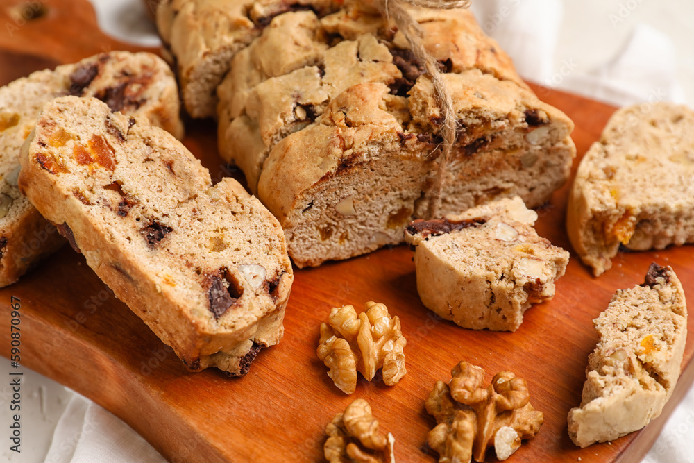 Wooden board with tasty biscotti cookies and walnuts, closeup