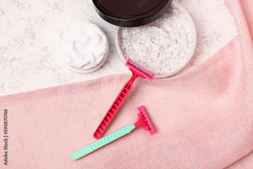 Safety razors, scrub and shaving foam on light background