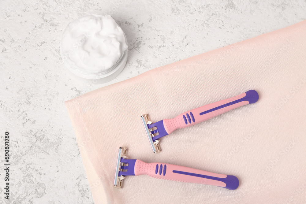 Safety razors and shaving foam on light background