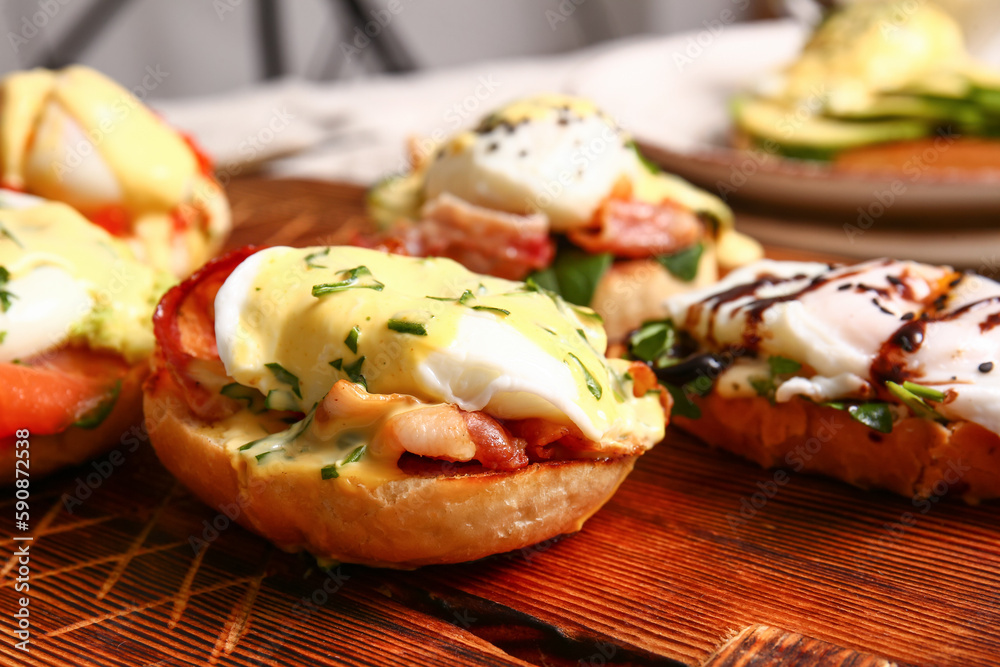 Board with different eggs Benedict on table, closeup