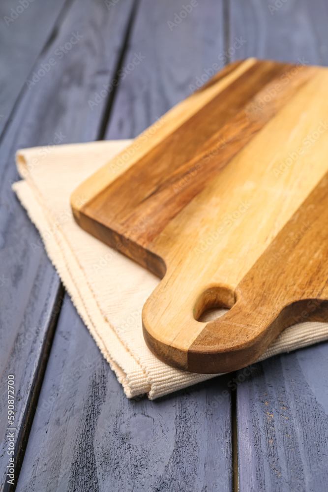 Kitchen board with napkin on color wooden background, closeup