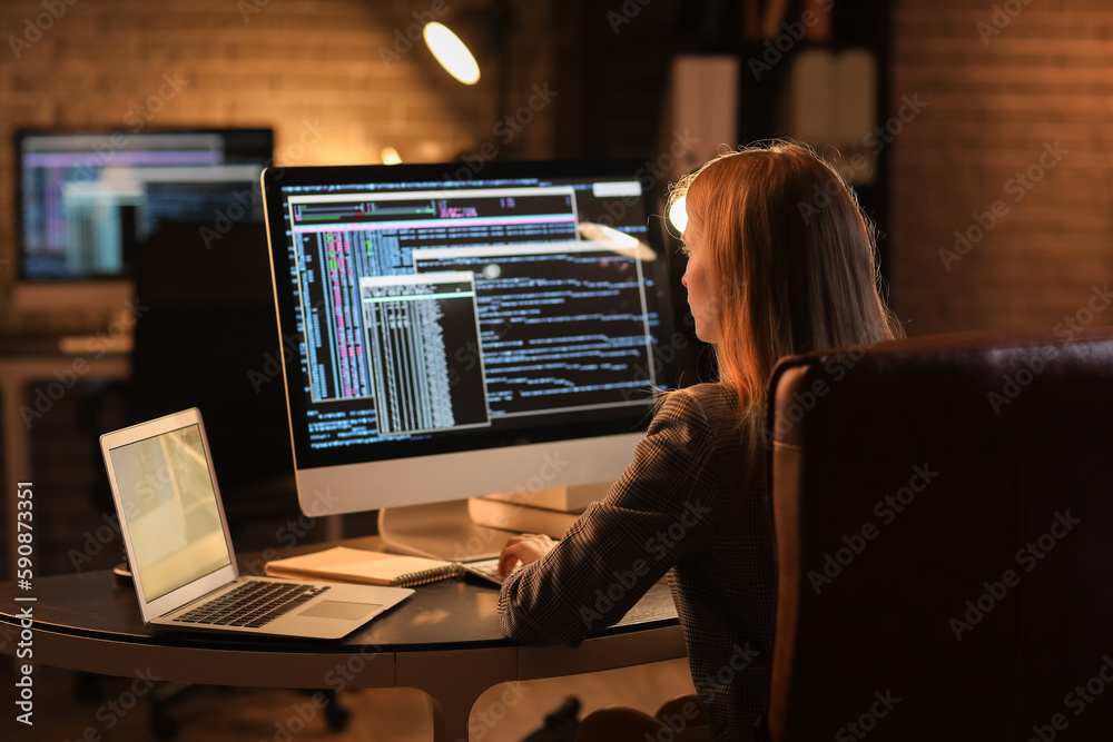 Female programmer working with computer in office at night