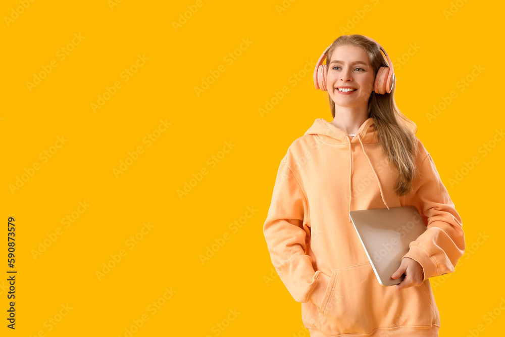 Female programmer in headphones with laptop on yellow background